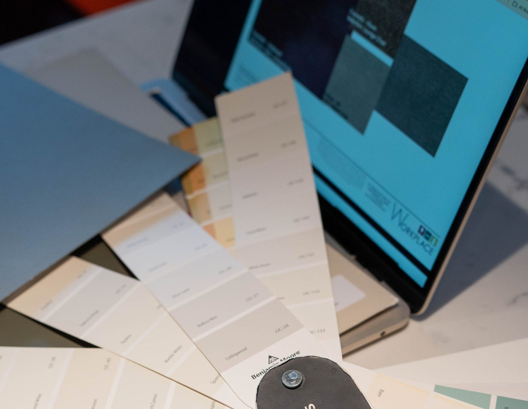 Photo of a laptop with a color swatch book laying on top of it.